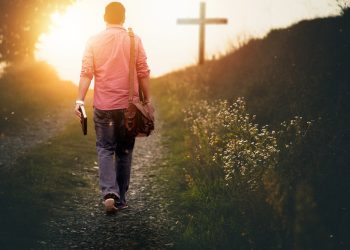 A man walking down the road with his bible in hand.