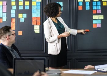 A woman standing in front of a wall with sticky notes on it.